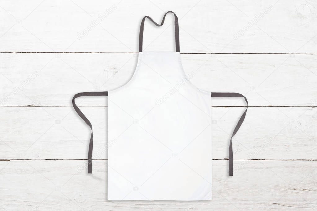 Blank white apron on wooden background