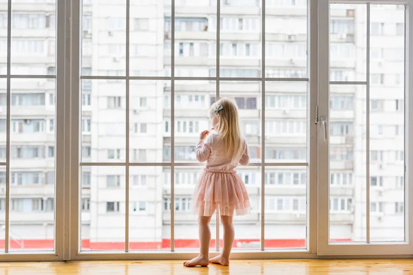 Happy little girl noszenie cute sukienka patrząc na okno — Zdjęcie stockowe