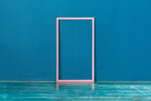 Cadru roz gol pe podea pe perete albastru — Fotografie, imagine de stoc