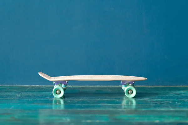 Skate de plástico no chão contra a parede azul — Fotografia de Stock
