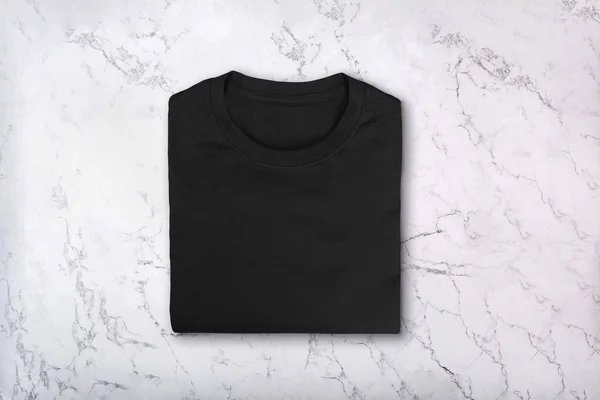 T-shirt de algodão preto em branco na textura de mármore — Fotografia de Stock