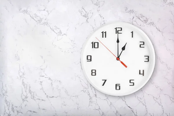 Reloj de pared redondo blanco sobre fondo de mármol natural blanco. Un reloj. — Foto de Stock