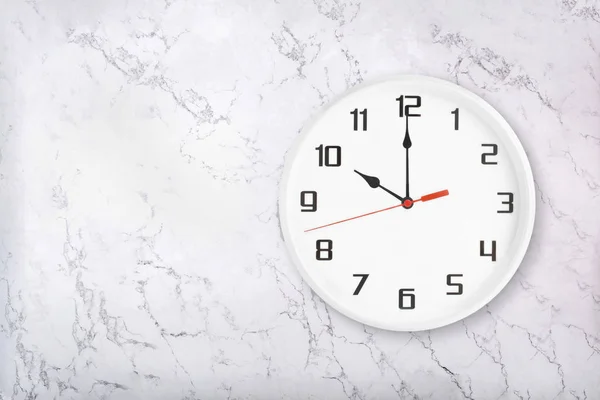 Biały okrągły zegar ścienny na białym naturalnym tle marmuru. Dziesięć godzin. — Zdjęcie stockowe