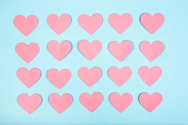Corações de papel rosa no fundo azul. Corações de papel cortados dispostos em linhas no fundo azul — Fotografia de Stock