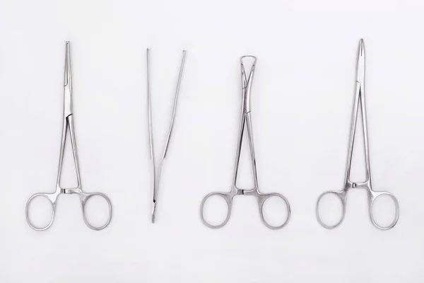 Flat lay of metal surgical instruments on white background — ストック写真