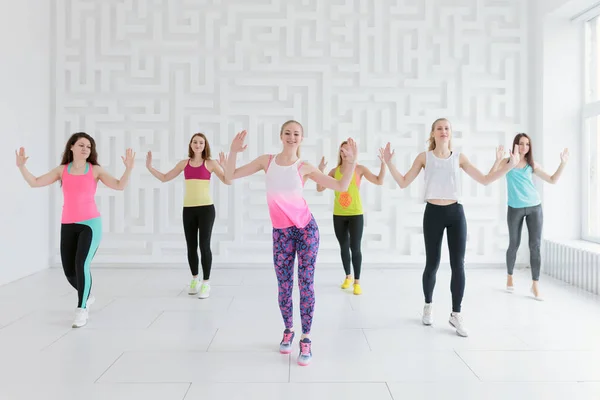 Junge Frauen in bunter Sportbekleidung beim Tanz-Fitness-Kurs im weißen Fitnessstudio — Stockfoto