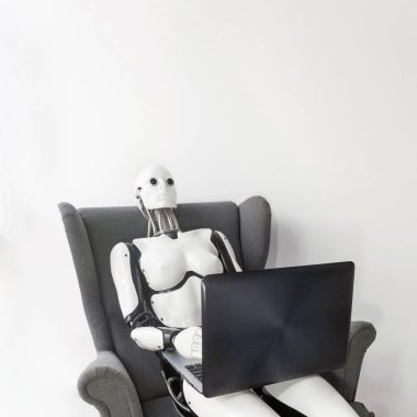 Robot working with laptop while sitting in armchair