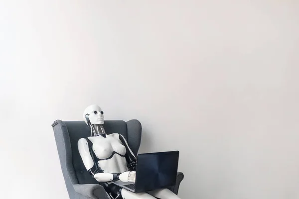 Robot pracuje s laptopem, zatímco sedí v křesle — Stock fotografie