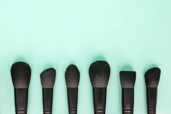 Flat lay van zwarte make-up borstels collectie op pastel groene achtergrond — Stockfoto