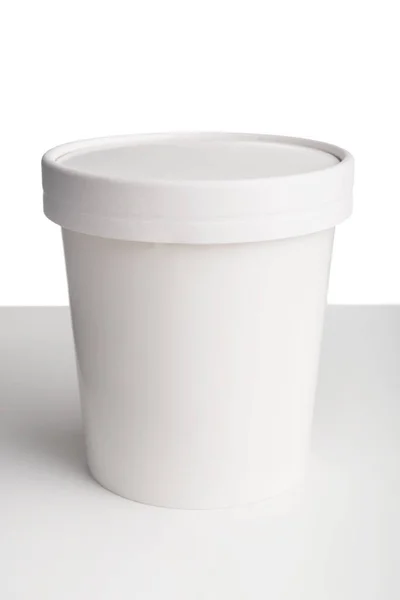 Coupe en papier blanc avec couvercle sur table blanche isolée sur fond blanc — Photo