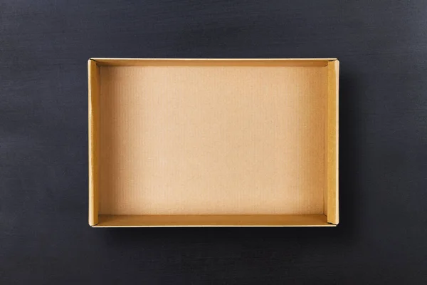 백보드 배경에 있는 개방 된 판지 상자. 검은 질감에 붙어 있는 빈 종 이 꾸러미 — 스톡 사진
