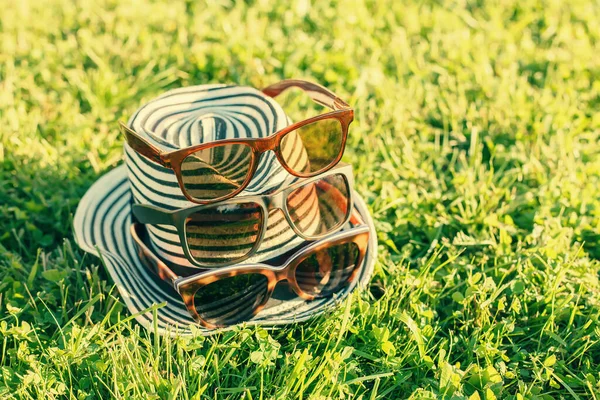 Sombrero femenino a rayas con varias gafas de sol —  Fotos de Stock