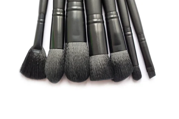 Close-up van een groep zwarte make-up borstels geïsoleerd op witte achtergrond. Vlakke lay-out van zwarte make-up borstels geïsoleerd op witte achtergrond — Stockfoto