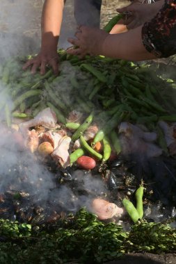 Achao, Şili - 6 Şubat 2016: Geleneksel Chilotan çanak Curanto al hoyo yerdeki bir deliğe hazırlanmaktadır. Kabuklu deniz ürünleri, et ve sebze katmanlı, sonra yapraklarla kaplı ve pişmiş. Muestras Gastronomicas 2016 fotoğrafı