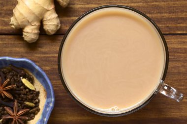 Ev yapımı Hint Masala Chai Çay siyah çay, baharat çeşitli yaptı ve ek yükü üzerinde koyu renkli ahşap doğal ışık (seçici odak, odak üstünde çay ile fotoğraflandı sütlü karışık)