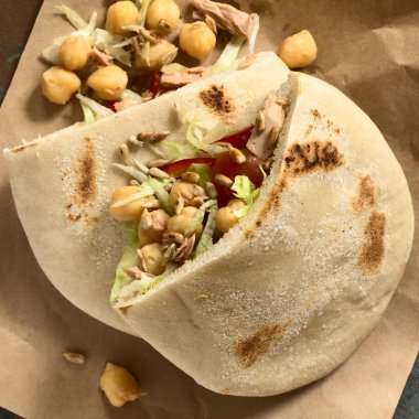 Pita sandviç doldurulmuş nohut, ton balığı, marul, biber, kiraz domates, üstte, kavrulmuş ayçiçeği çekirdeği ile fotoğraflandı doğal ışık (seçici odak, odak üst pide doldurma ile ek yükü)