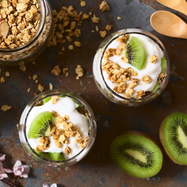 Taze kivi ve gevrek badem ve yulaf ezmesi granola gözlük, yoğurt parfe fotoğrafı üzerinde barut doğal ışık (seçici odak, odak üstünde parfait ile ek yükü)