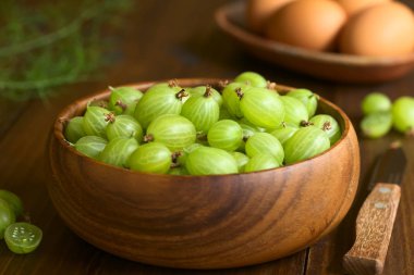 Ahşap kase üzerinde koyu renkli ahşap doğal ışık (seçici odak, odak kase ortasında üst bektaşi ile fotoğraflandı ham bektaşi (lat. Ribes uva-crispa))