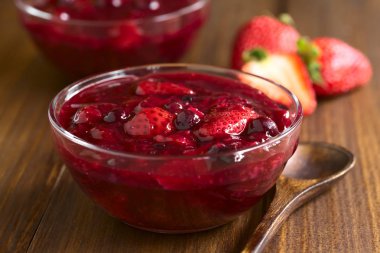 Çilek, böğürtlen, ahududu ve şeker ve nişasta, pişmiş redcurrants yapılmış Almanca Rote Gruetze (kırmızı kabuğu çıkarılmış tane) kırmızı dut puding fotoğrafı doğal ışık (seçici odak, odak üçte biri haline tatlı ile ahşap üzerine)