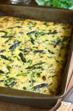 Yumurta, yeşil kuşkonmaz, bezelye, mavi peynir, maydanoz ve kahverengi pirinç pişirme çanağı içinde yapılmış frittata fotoğrafı doğal ışık (seçici odak, odak üçte biri haline görüntü ile)