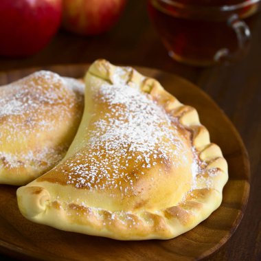 Doğal ışık (seçici odak, odak üçte biri haline görüntü ile koyu ahşap üzerine krema şeker, çay arkada ile Şili elma empanada fotoğrafı)