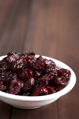 Koyu renkli ahşap doğal ışık (seçici odak, odak üstünde belgili tanımlık tepe cranberries ile fotoğraflandı kurutulmuş cranberries küçük kapta)