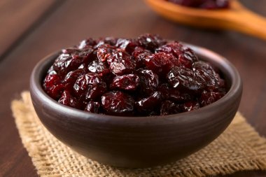 Koyu renkli ahşap doğal ışık (seçici odak, odak üstünde belgili tanımlık tepe cranberries ile fotoğraflandı kurutulmuş cranberries küçük rustik kapta)