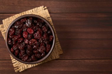 Ek yükü üzerinde koyu renkli ahşap doğal ışık (seçici odak, odak üstünde belgili tanımlık tepe cranberries ile fotoğraflandı kurutulmuş cranberries küçük rustik kapta)