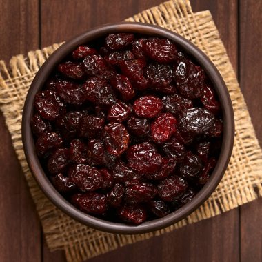 Ek yükü üzerinde koyu renkli ahşap doğal ışık (seçici odak, odak üstünde belgili tanımlık tepe cranberries ile fotoğraflandı kurutulmuş cranberries küçük rustik kapta)