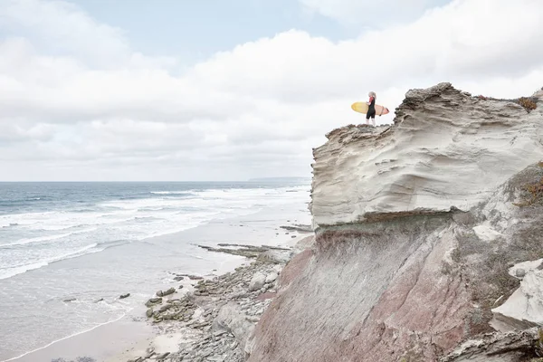 Surfer girl on cliff near ocean — Stock Photo, Image