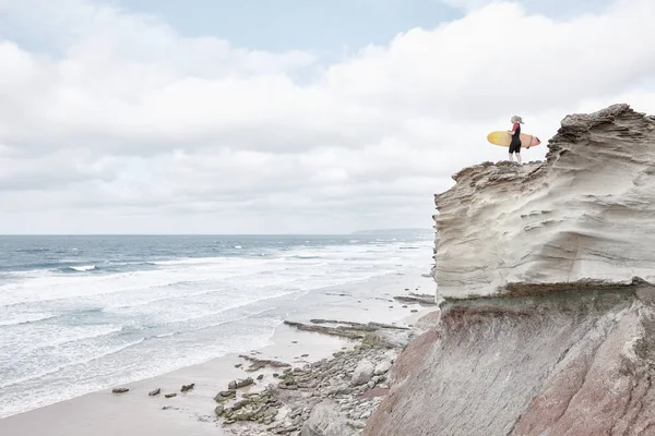 Surfer girl på klippa nära havet — Stockfoto
