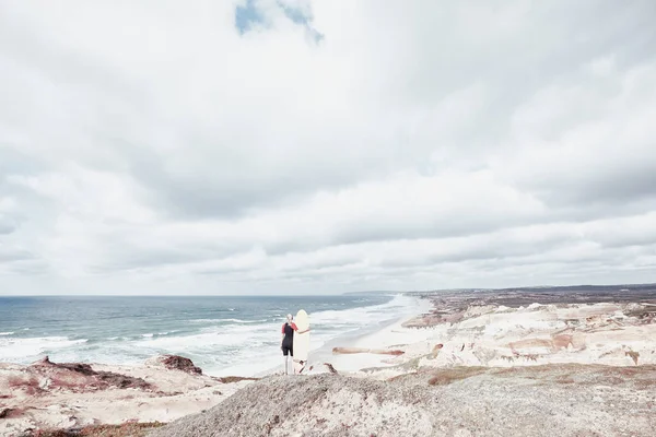 Девушка-серфер на скале у океана — стоковое фото
