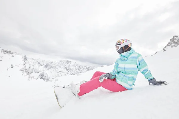 Jonge zittende vrouw met snowboard — Stockfoto