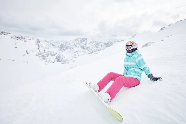 Jeune femme assise avec snowboard — Photo