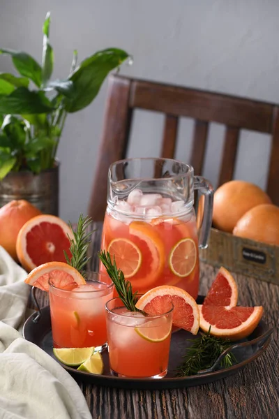 Fresh grapefruit cocktail. Fresh summer cocktail with grapefruit, lime, sprig of rosemary and ice cubes.