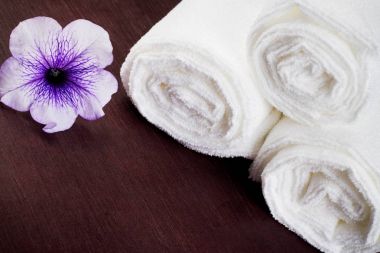 Beyaz rulo havlu ile mor çiçek içine bükülmüş