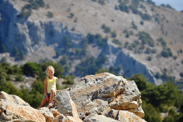 Schönes Mädchen sitzt auf einem Felsen — Stockfoto