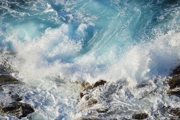 Golven spatten op stenen — Stockfoto