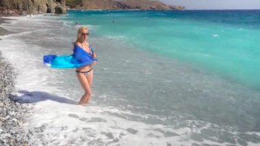 mavi deniz ile sahilde yürüyen genç kadın