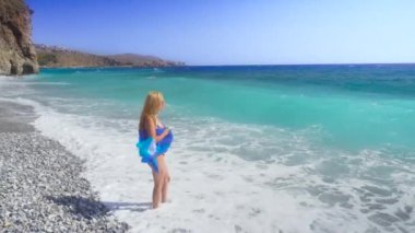mavi deniz ile sahilde yürüyen genç kadın