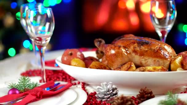 Roasted chicken on christmas table in front of fireplace and tree with lights — Stock Video