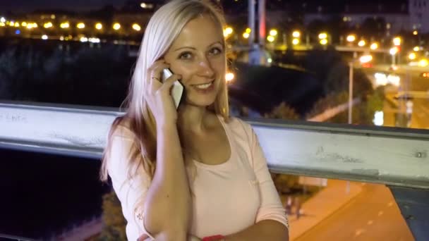 Жінка розмовляє телефоном у нічному місті — стокове відео