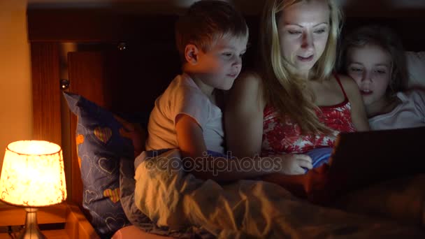 Мама с детьми читает книгу — стоковое видео