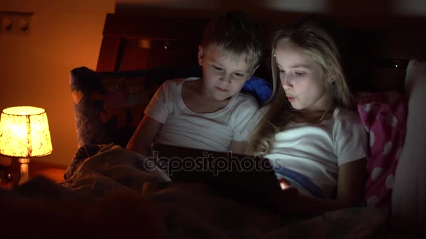 Kinderen spelen tablet in bed — Stockvideo