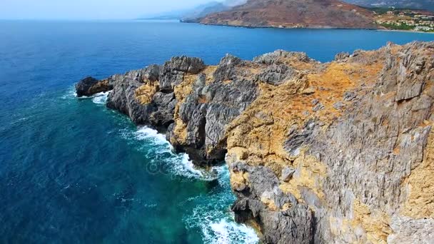 नीला सागर, तट पर चट्टानों में लहरें टूट रही हैं — स्टॉक वीडियो
