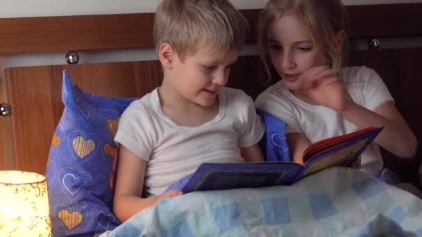 Lindo niños leyendo libro en la cama — Vídeo de stock