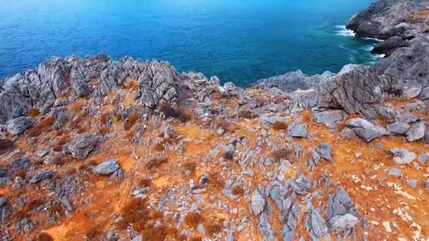 Blauwe zee, de golven breken in de kliffen aan de kust — Stockvideo