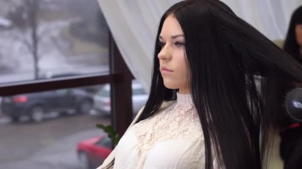 Молодая привлекательная женщина с длинными черными волосами с стрижкой волос в салоне красоты — стоковое видео