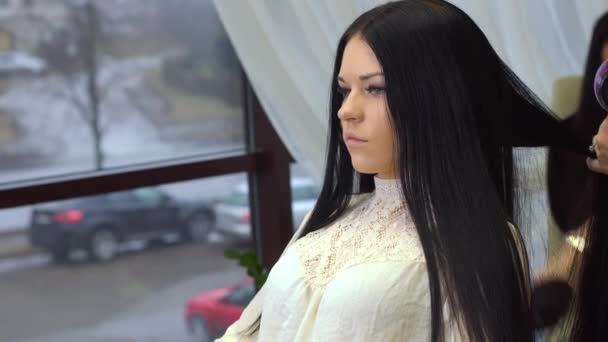 Jeune femme attrayante avec de longs cheveux noirs ayant coupe de cheveux au salon de beauté — Video