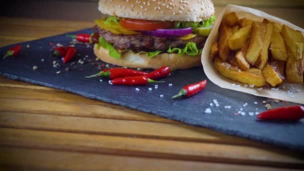 Sabrosa hamburguesa casera con patatas servidas en plato de piedra — Vídeo de stock